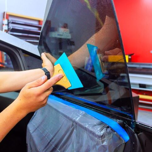 Car window tinting process in workshop with skilled technician applying film